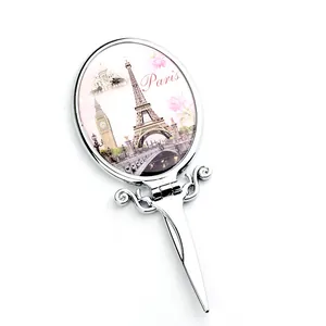 Detailed view of foldable silver metal hand mirror with vintage Paris landmark illustration