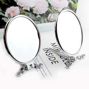 Detail of two oval vintage silver mirrors with ornate scrollwork and folding stands
