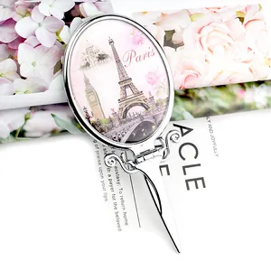 Vintage silver handle makeup mirror with Paris Eiffel Tower design and floral background