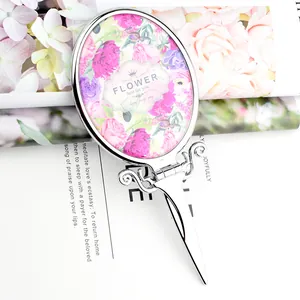 Mini folding handheld cosmetic mirror with elegant floral pattern and silver scroll handle