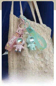 Detail of pink and green astronaut keychains with space straps on a woven straw bag