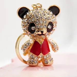 Detail of a sparkling crystal-encrusted panda keychain with golden hardware on pink background