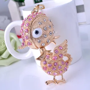 Detail of cartoon bird keychain with gold metal base and pink crystal rhinestones