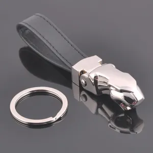 Detail of silver jaguar head keychain with black leather strap on reflective dark background