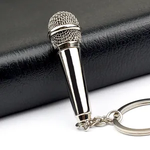 Polished silver microphone keychain with realistic metal mesh texture on black leather background
