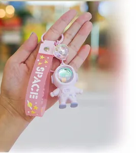 Pink astronaut keychain with glowing ball and space strap shown in hand detail