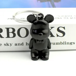 Detail of a matte black bear keychain with silver ring on white decorative books