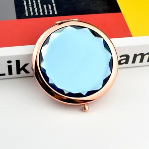 Close-up of rose gold folding compact mirror with a faceted dark blue crystal inlay