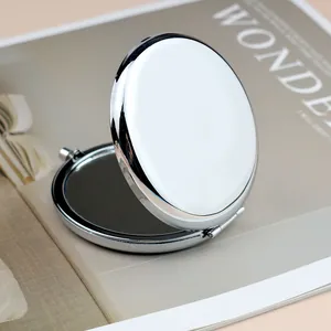 Polished silver metal round folding makeup mirror shown on a magazine background