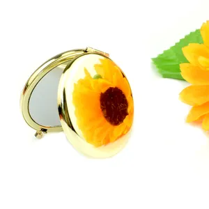 Golden pocket compact mirror with sunflower design shown in semi-open view