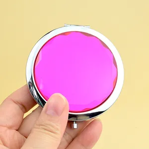 Pink crystal round folding makeup mirror with elegant silver metal frame held by hand