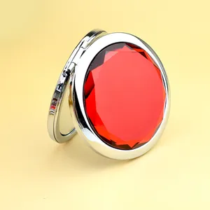Silver folding pocket mirror with a large faceted red gemstone and sleek metal finish