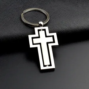 Porte-clés croix rotative en métal argenté poli sur fond de cuir noir texturé