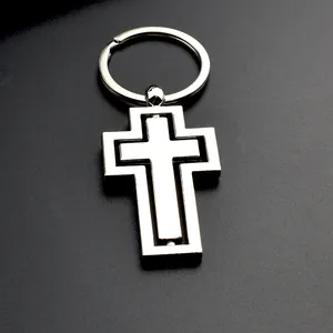Détail du porte-clés croix en métal argenté rotatif avec structure interne pivotante