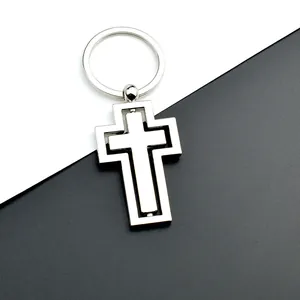 Gros plan d'un porte-clés croix en métal rotatif avec une finition argentée et polie