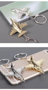 Detail of silver and gold fighter jet keychains resting on a glossy smartphone surface