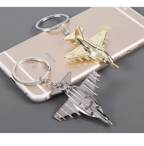 Macro detail of polished gold and silver fighter jet keychains on a metallic surface