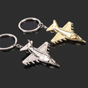 Polished gold and silver fighter jet model keychains on a reflective black surface