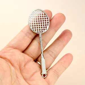 Polished silver metal badminton racket keychain pendant held in hand for scale