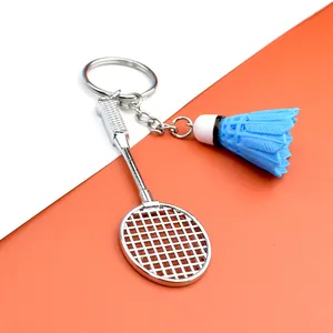 Dettaglio del portachiavi con racchetta da badminton argento e volano blu su sfondo bicolore