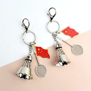 Detail of silver badminton racket and shuttlecock keychain with a small red flag charm