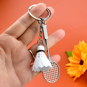 Dettaglio del portachiavi con racchetta da badminton in lega e volano bianco su sfondo vivace