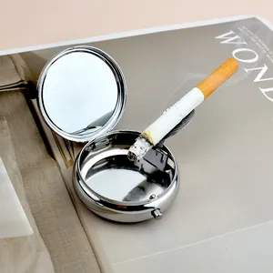 Detail of portable silver metal ashtray with built-in mirror and folding cigarette holder