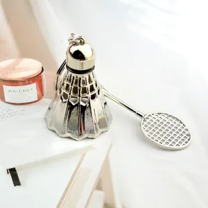 Detailed close-up of metallic silver badminton and racket keychain on desk