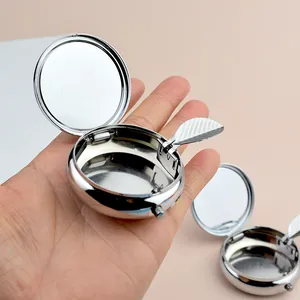 Portable silver round metal pocket ashtray with flip lid and mirror shown in hand