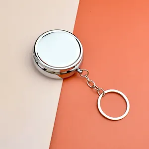 Gros plan d'une boîte à pilules ronde en métal argenté poli avec porte-clés de voyage