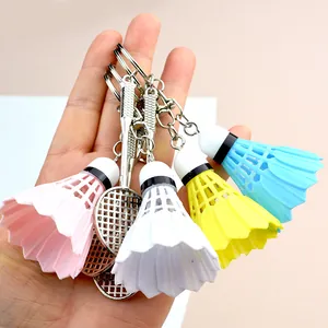 Detailed view of colorful plastic shuttlecock and metal racket keychains held in hand