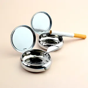Detail view of two portable round metal ashtrays with a flip-top lid and cigarette holder