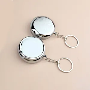 Lot de deux boîtes à pilules en métal argenté poli avec porte-clés sur fond beige