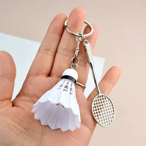 Handheld shot showing the scale of the silver badminton racket and shuttlecock keychain