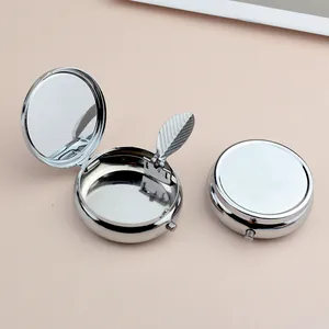 Portable silver round metal ash box with internal mirror and secure press closure