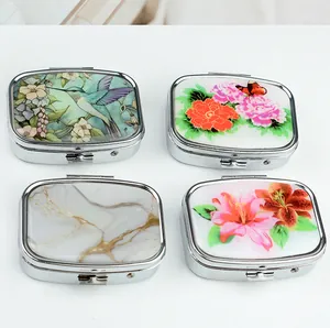 Close-up of four portable metal pill boxes with floral and marble patterned lids