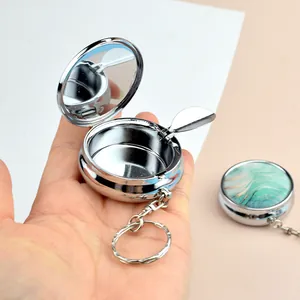 Detail of portable metal ashtray with green marble lid and integrated interior mirror