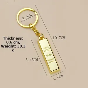 Macro shot of gold bar keychain showing dimensions and weight details on flat surface