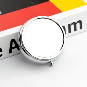 Boîte à pilules ronde en métal argenté avec bouton-poussoir vue sous un angle de 45 degrés