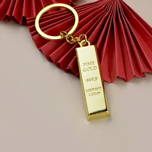 Detail shot of a solid gold bar keychain with Fine Gold 999.9 engraving on a red fan