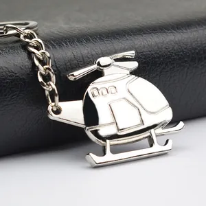 Polished silver metal helicopter keychain with propeller detail on black leather background
