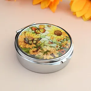 Détail d'une boîte à pilules ronde en métal avec motifs vintage de tournesol et papillon