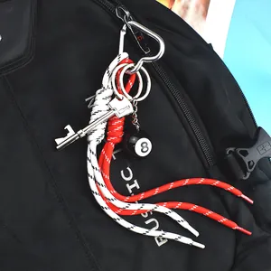 Creative keychain with red woven rope, metal key charm and black 8 ball on a backpack