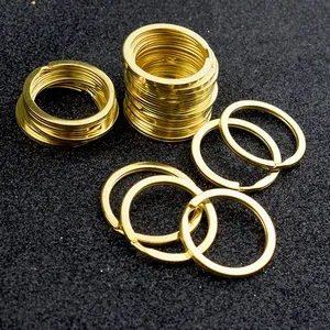Detailed view of polished gold metal flat key rings scattered on a black matte background