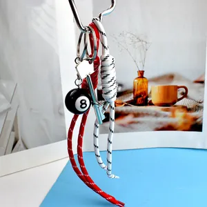 Detail of No.8 billiard ball keychain with silver key charm and woven cord straps