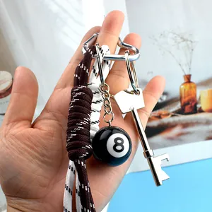 Detail of sports keychain with black 8 pool ball, braided rope and key bottle opener