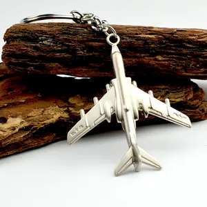 Llavero de avión realista en metal plateado mate sobre fondo de madera natural
