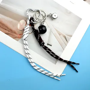 Vue détaillée d'un porte-clés tendance avec dé en métal, perle noire et cordes tressées