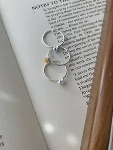 Detailansicht von S925 Silberringen mit bunten Zirkonsternen auf Vintage-Buchseiten