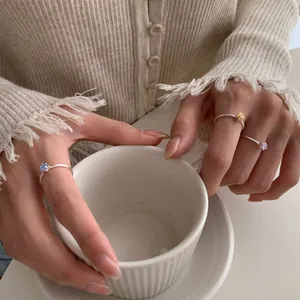 Drei zierliche S925 Silberringe mit farbigen Sternsteinen beim Halten einer Tasse